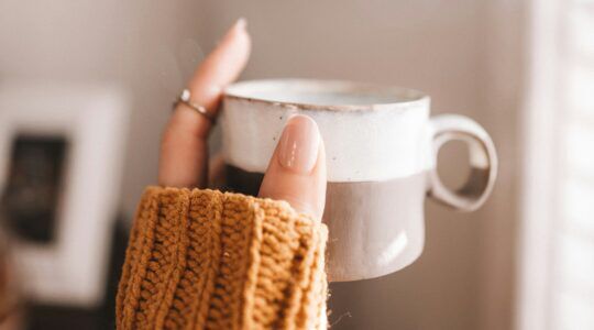 Een vrouw die met koude handen een kop vasthoudt