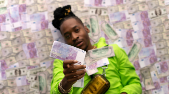 Jongvolwassene met een briefje van vijfhonderd euro liggend op een bed van contant geld.