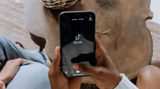 Een man die op zijn telefoon op de app 'TikTok' zit (deze app kan zeker een dopaminetekort veroorzaken)