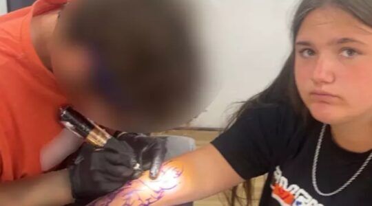 De tiener terwijl de wanstaltige tattoo wordt gezet.