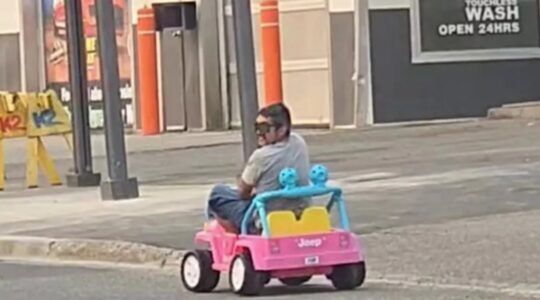 Man die wordt aangehouden in een roze speelgoedauto