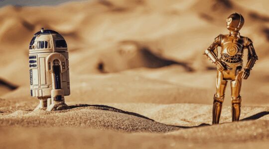 R2-D2 and C-3PO splitting up in a desert in the Star Wars universe door Christian Maass op Unsplash