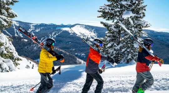 Drie vakantiegangers lopen een berg op met ski's