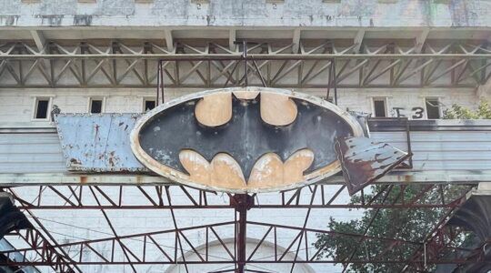 Verwoest Batman-logo boven de ingang van de verlaten nachtclub