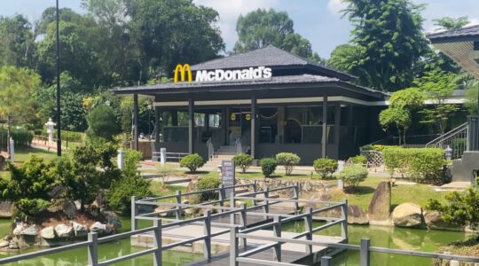 Een McDonald's gebouw omringd met een vijver, brug en bomen