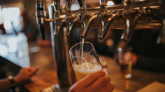 Close-up van iemand die een glas bier tapt in een kroeg