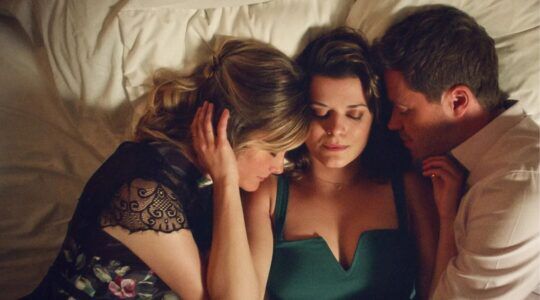 Een man en twee vrouwen die samen in bed liggen.