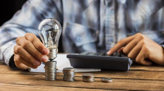 Een man die berekend hoeveel geld hij moet betalen om zijn lampje te laten branden, wat te danken is aan de tariefregels van 2027.