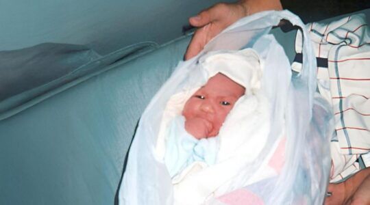 Een baby gewikkeld in een theedoek en een plastic zak.