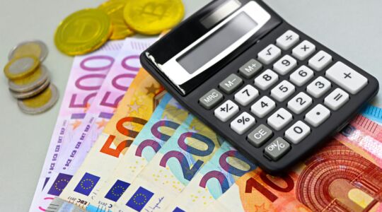 Een hele hoop geld (zowel brief- als muntgeld) naast een rekenmachine