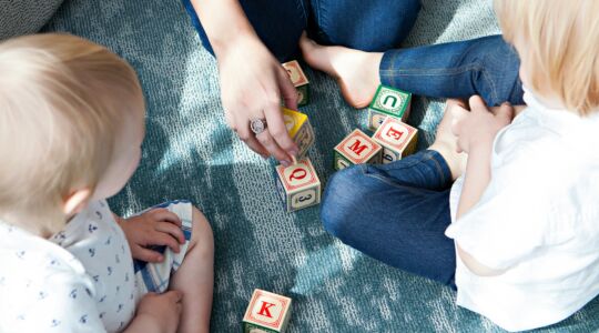 Een moeder die met haar kinderen speelt op een kleedje.