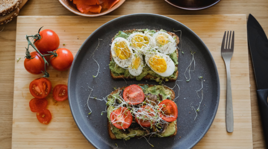 Twee broodjes belegd met ei, tomaat en avocado.