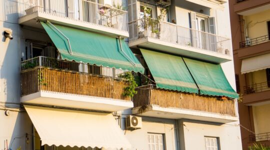 Twee zonneschermen die voor een balkon hangen.