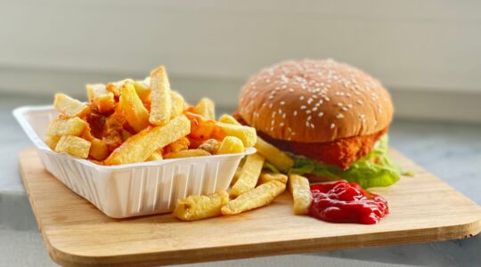 Een patatje en een hamburger die op een plank liggen.
