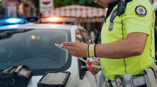Een politieman die een boete uitschrijft, wellicht voor iemand die met de auto op vakantie is.