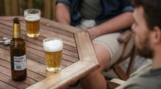 Mannen die aan een tafel bier aan het drinken zijn.