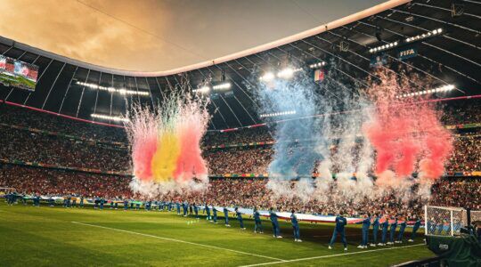 Voetbalwedstrijd in het stadion met vuurwerk en vlaggen.