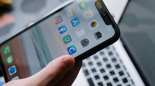Een iPhone die boven een laptop wordt gehouden.