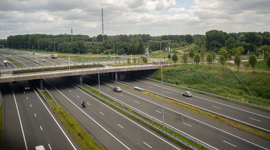 Een nederlandse snelweg, er rijden een paar auto's op de weg
